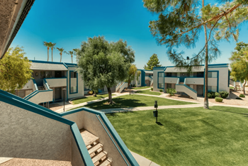 a group of apartments with a lawn and trees